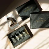 Bellekin parfum discoveryset , een open en anders dicht. Zwarte doosjes met gouden letters in de zon met schaduw lichtval met kaartje