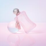 Parfums de Marly Delina La Rosee parfumsfles ligt op een doorzichtige glazen bol met rose achtergrond