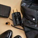 Parfum de Marly Oajan zwarte parfumfles liggend naast een tas, zwarte telefoonhoesje alsof het uit de tas is gevallen