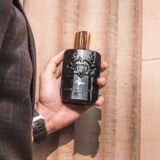 Man hous zwarte parfumfles van Parfum de Marly Oajan vast in hand